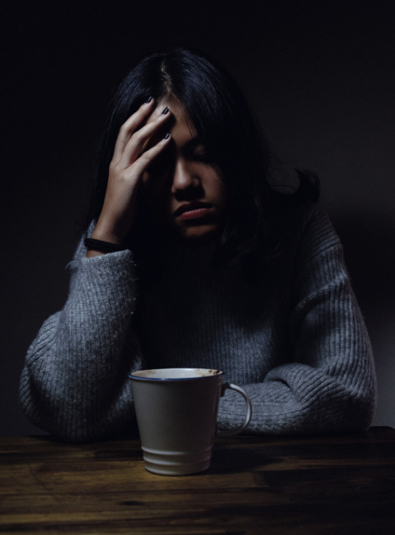 A woman sitting with a coffee experiencing an ocular migraine