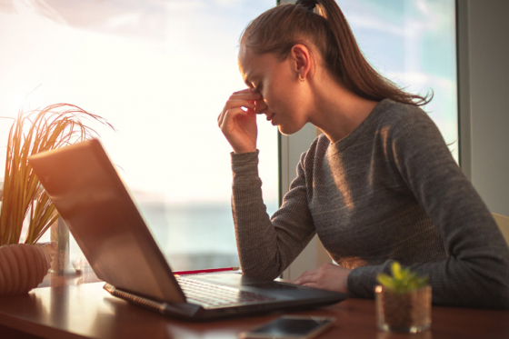Woman working on computer next to window becomes sensitive to light due to eye strain